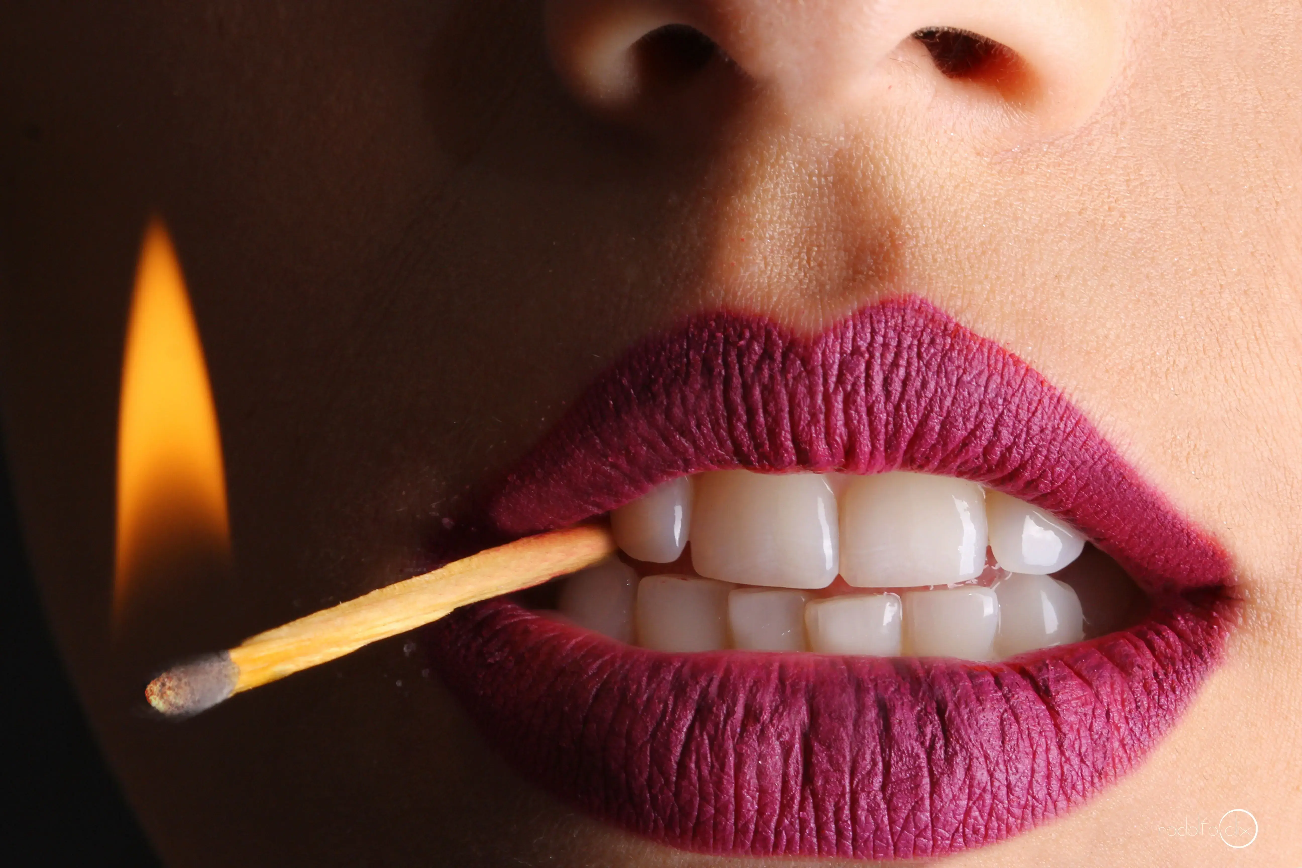 Close-up of lips holding a lit match — Lip Liquid campaign shot
